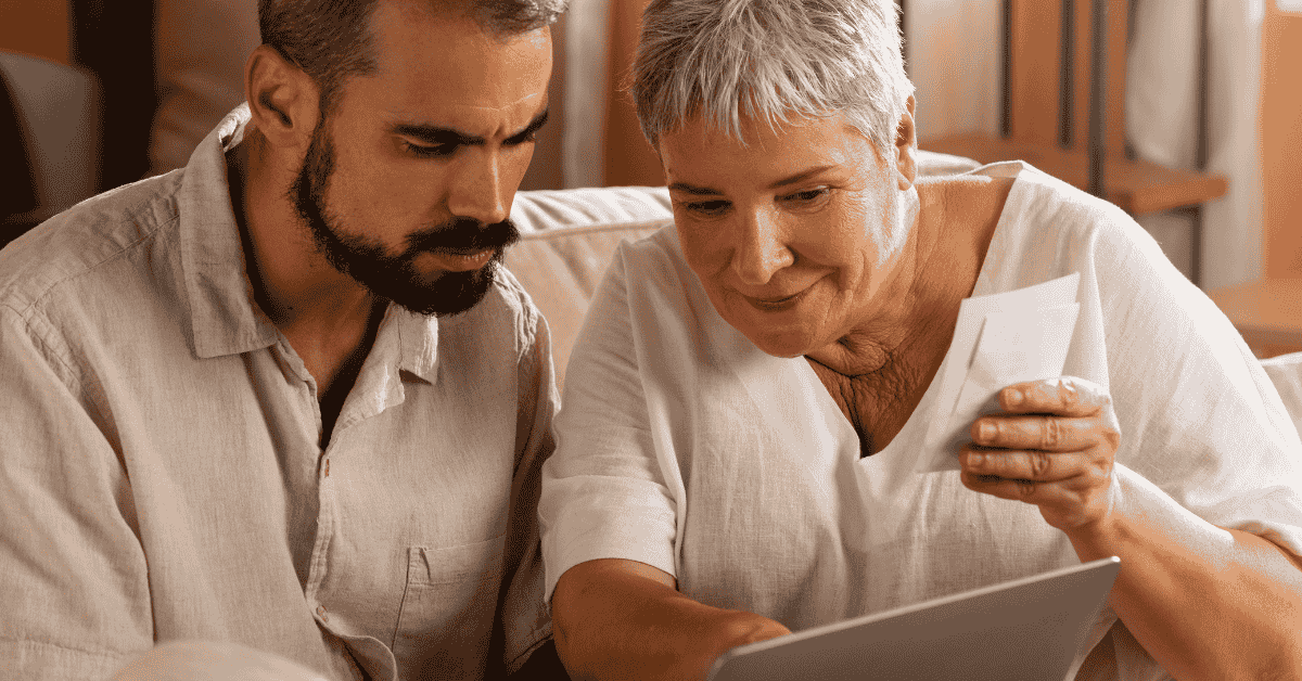 Mulher mais velha e homem adulto analisando documentos e informações no laptop enquanto organizam finanças para solicitar um empréstimo.